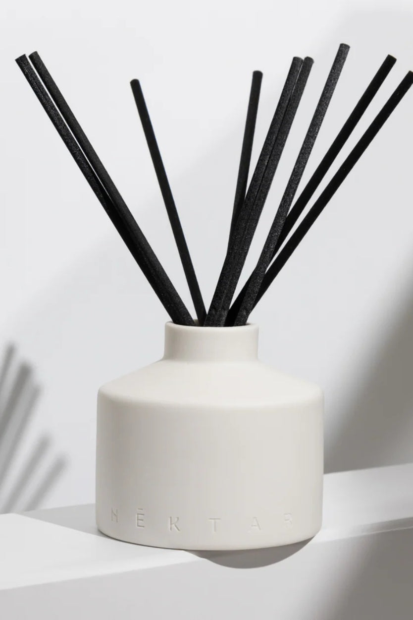White diffuser with black sticks on a light background