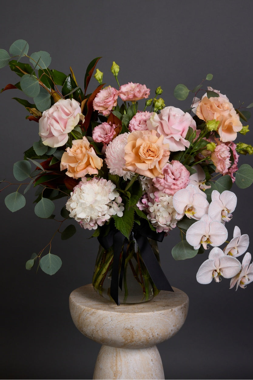 A naturally styled bouquet of seasonal blooms in hues of perfect peach, apricot, and varying pinks combined with textural foliages delivery melbourne