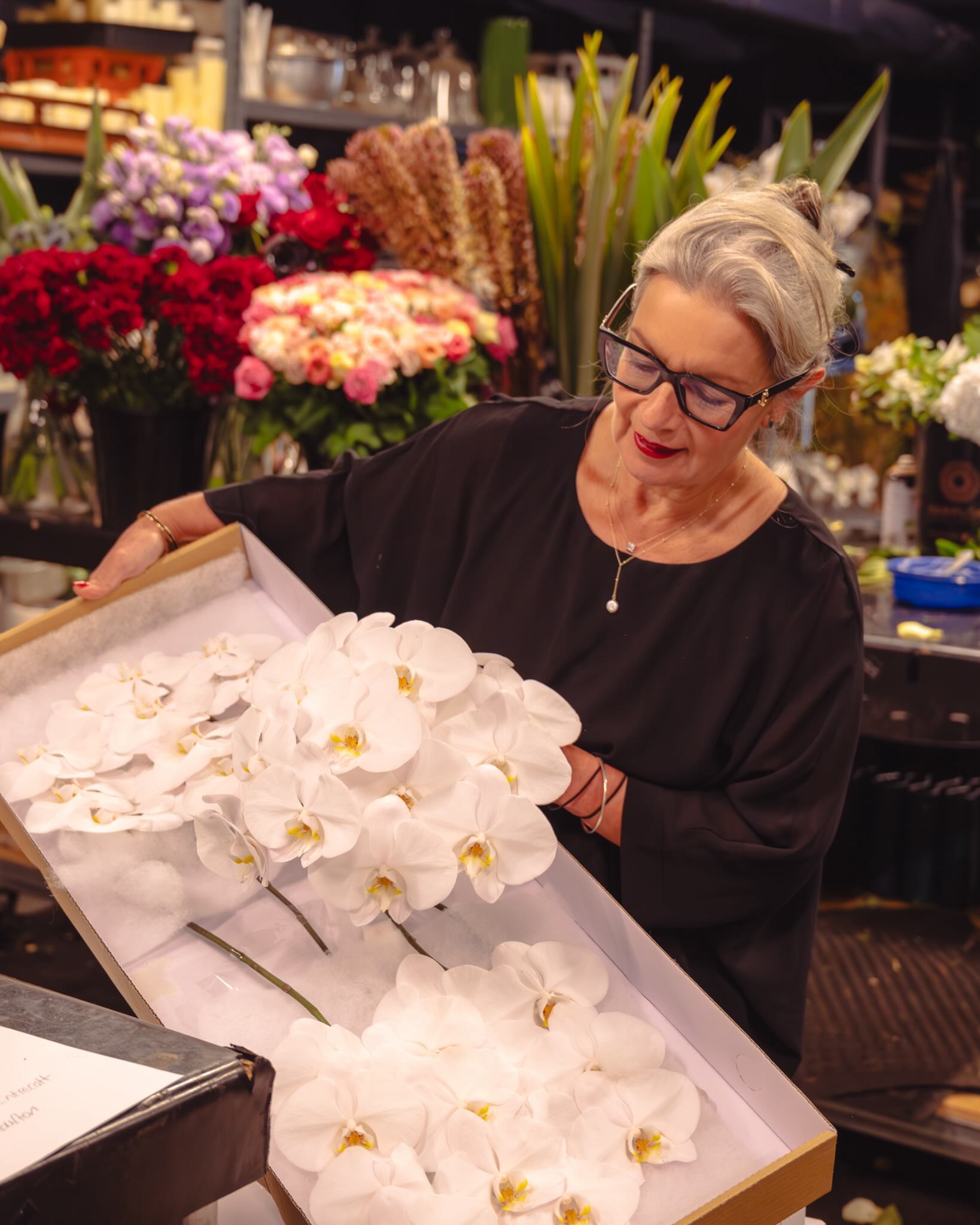 Victoria Whitelaw carefully wrapping a white phalaenopsis orchid in signature embossed paper