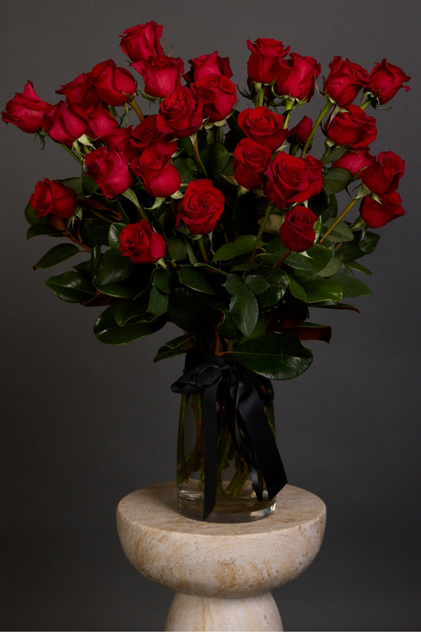 a big beautiful bouquet of imported, large-headed red roses with lush seasonal foliage