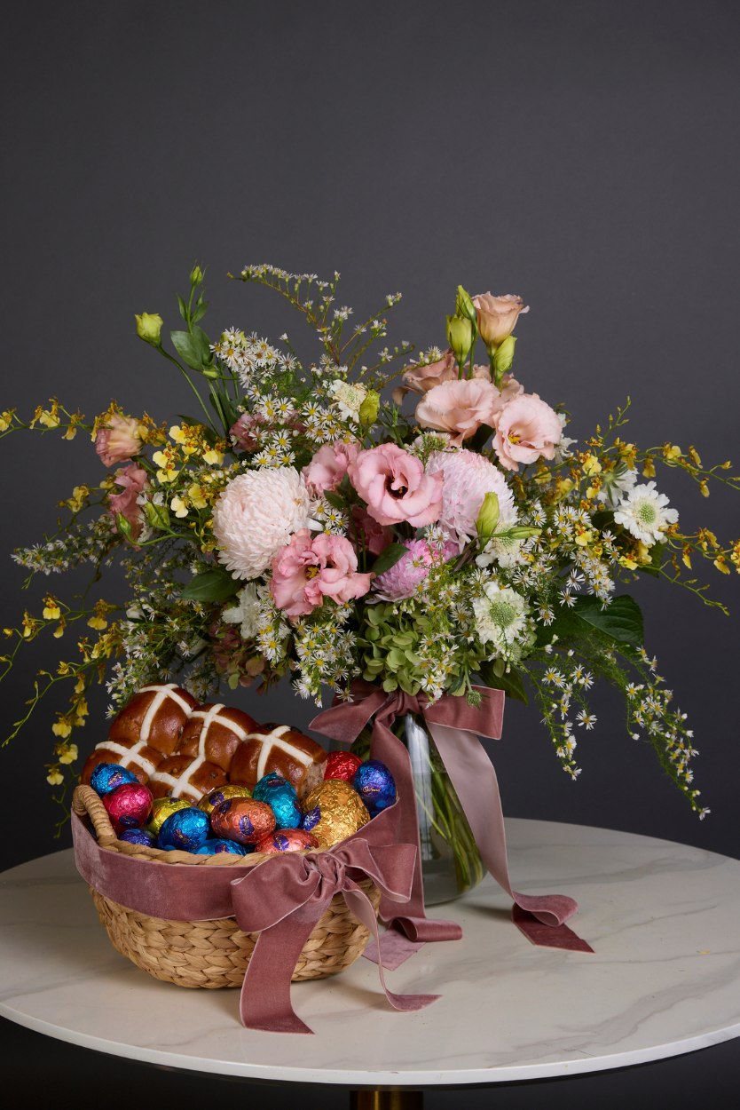 Floral arrangement with a basket of Easter eggs on a dark background