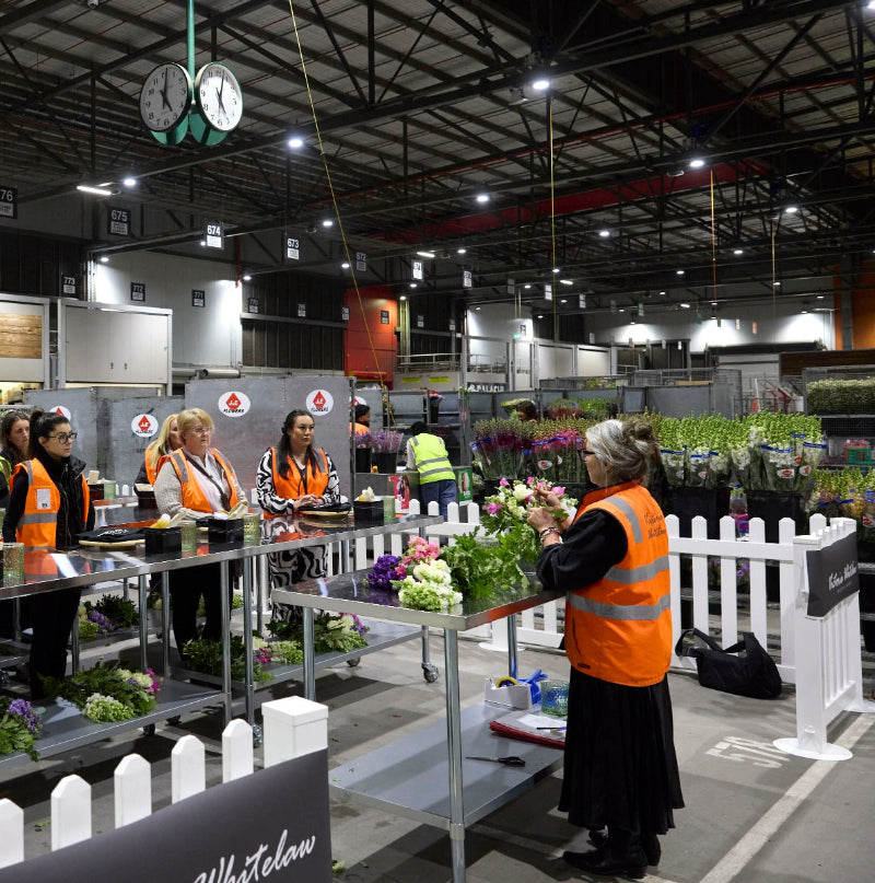 People doing a workshop in a warehouse setting with floral arrangements.