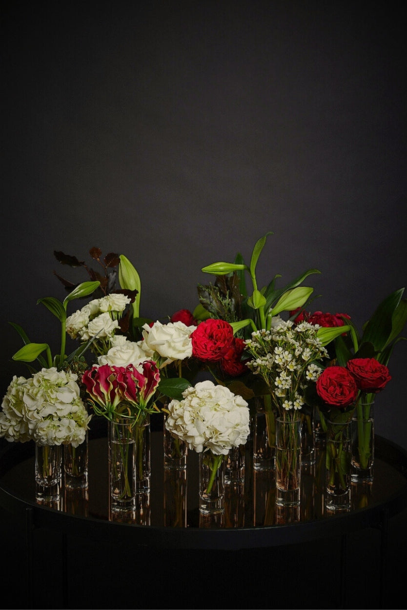 Bouquets of red and white flowers in clear vases bud vases for dinner parties