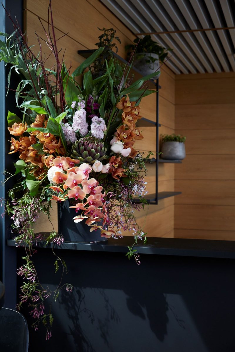 Decorative floral arrangement with a wooden wall and shelf in the background