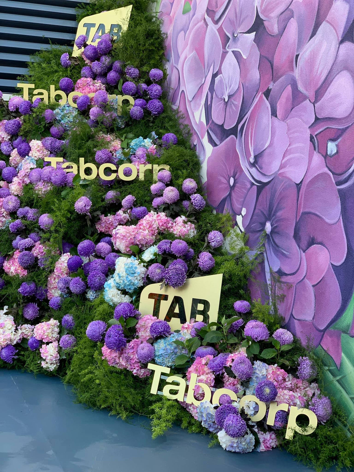 Decorative floral arrangement with 'Tabcorp' branding and purple flowers.