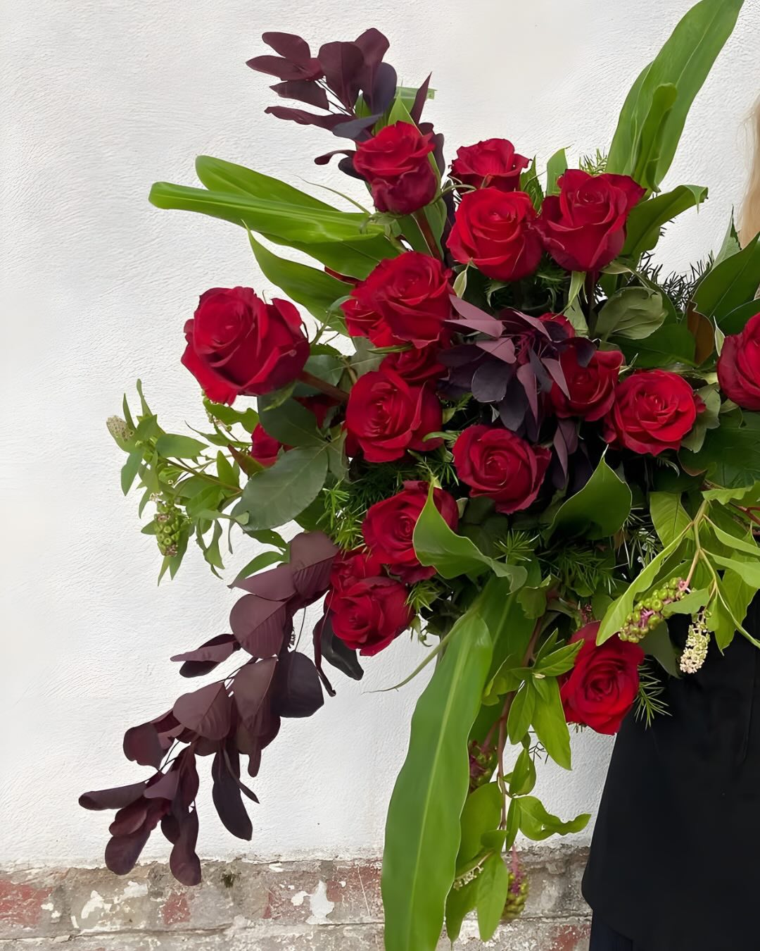 Bouquet of red roses with green leaves against a white background