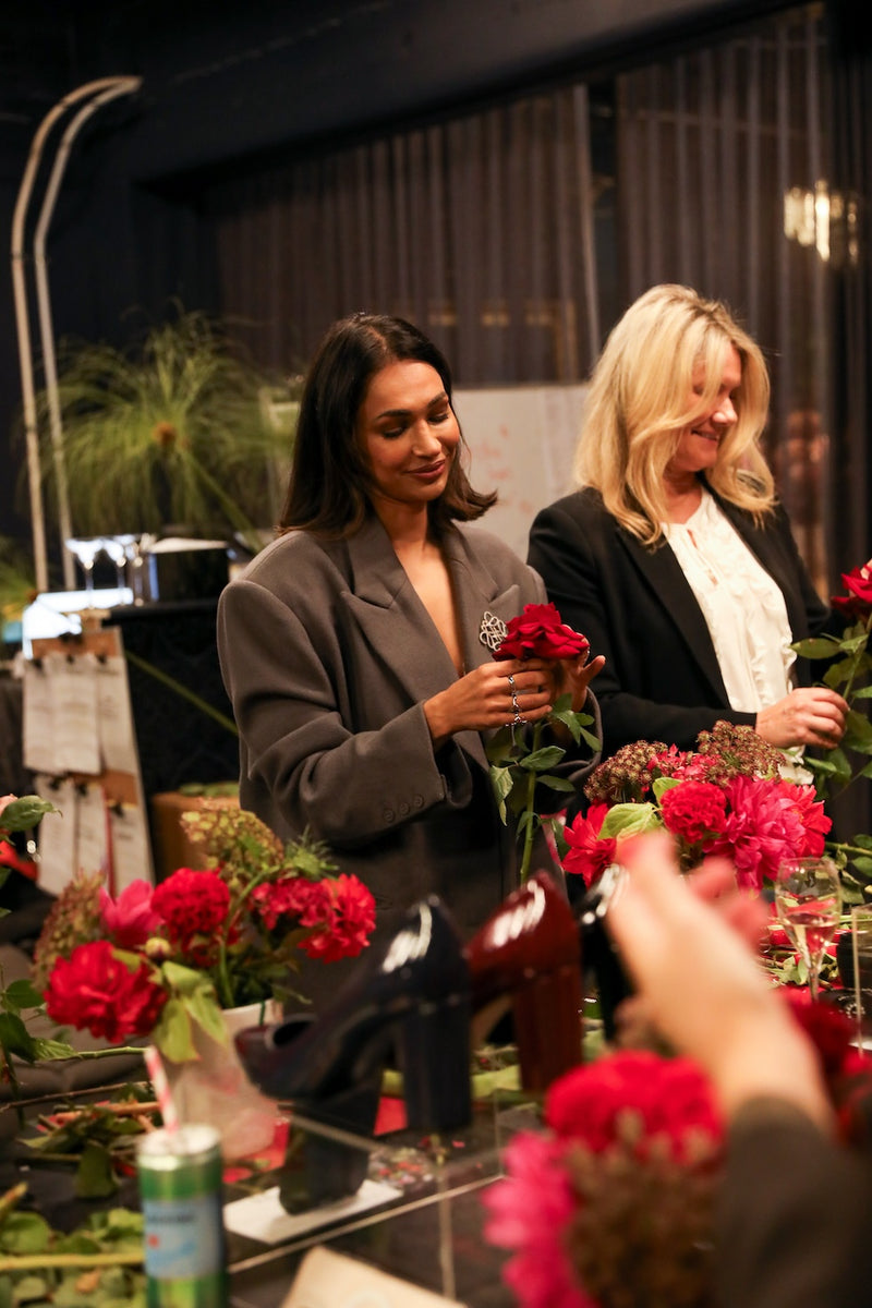 Two women arranging flowers at a table with a blurred background