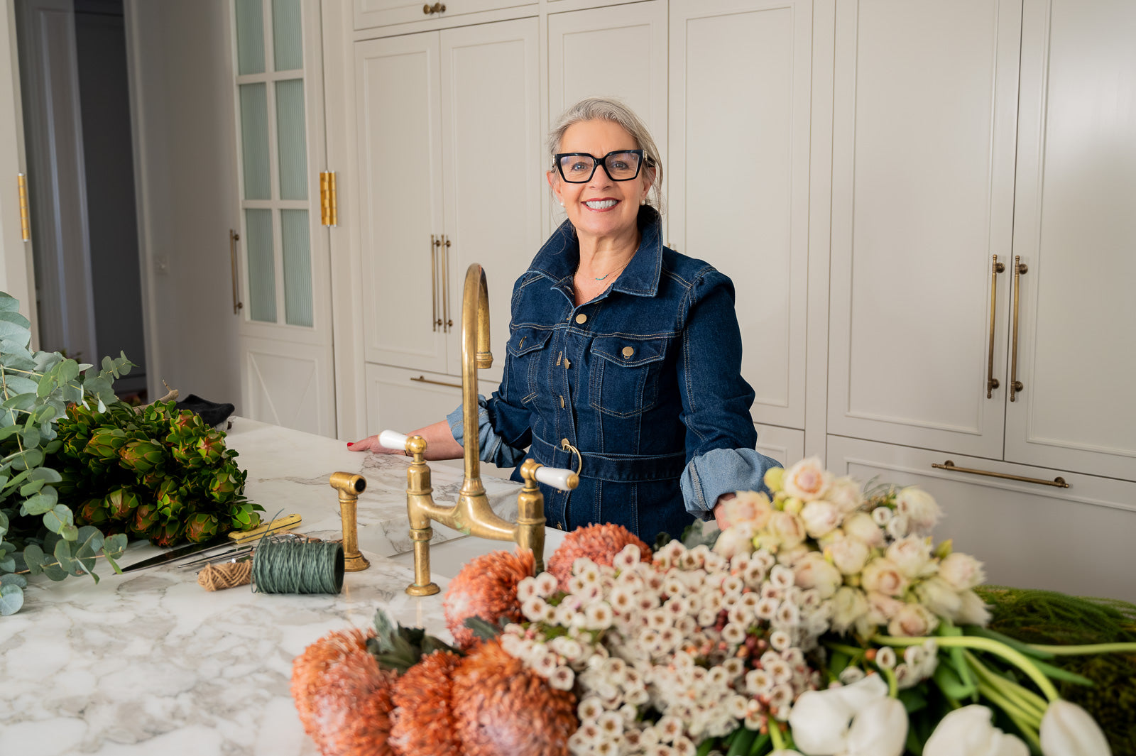 Woman in a kitchen with flowers and decorative items on the counter 'How to prepare flowers for longevity'