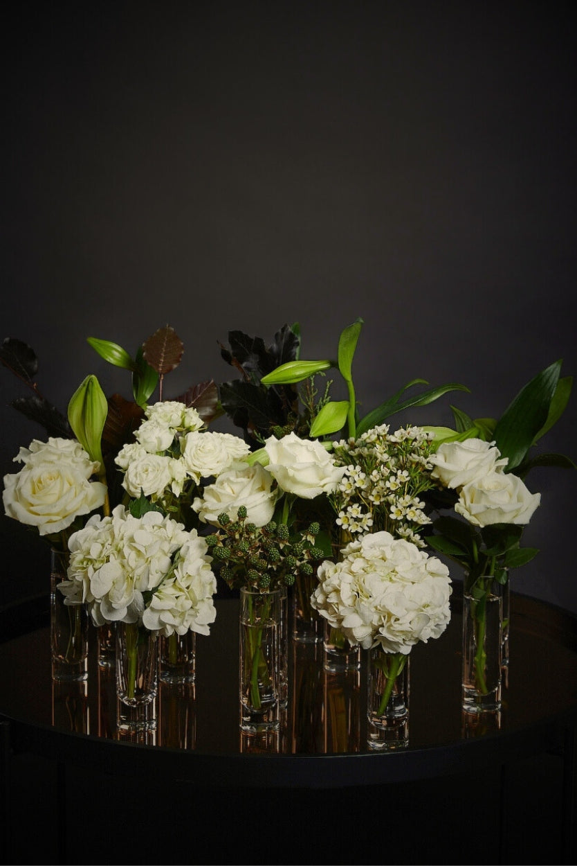 Bouquets of white flowers in clear bud vases for christmas table styling